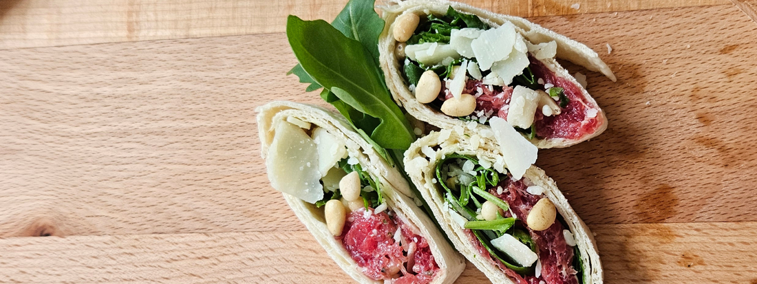 Carpaccio rolletjes gevuld met truffelmayonaise en Parmezaanse kaas, perfect geserveerd op een borrelplank.
